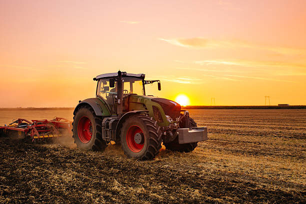 tracteur dans un champ au couche du soleil
