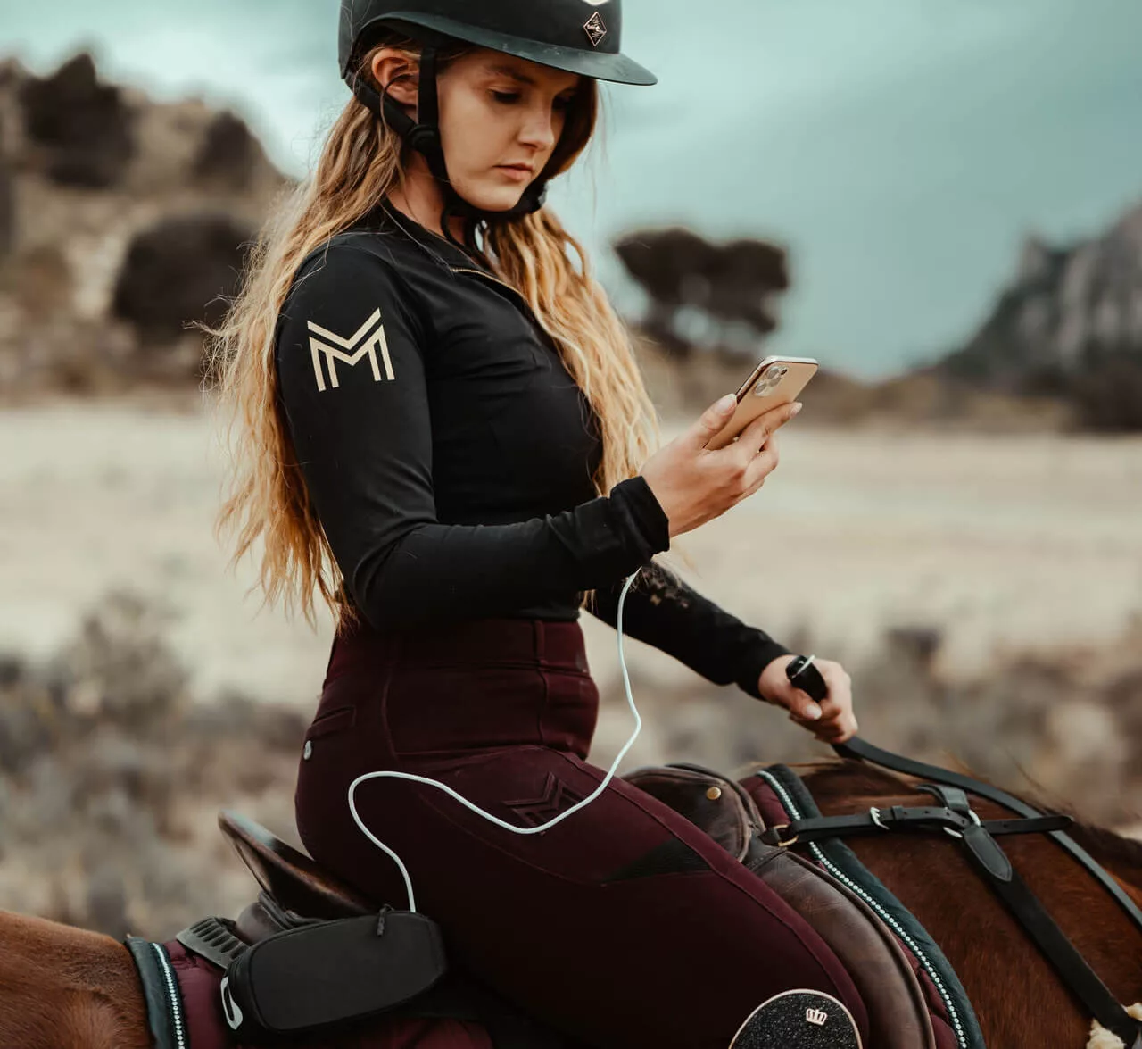 Une cavalier sur sont cheval avec un telephone en main